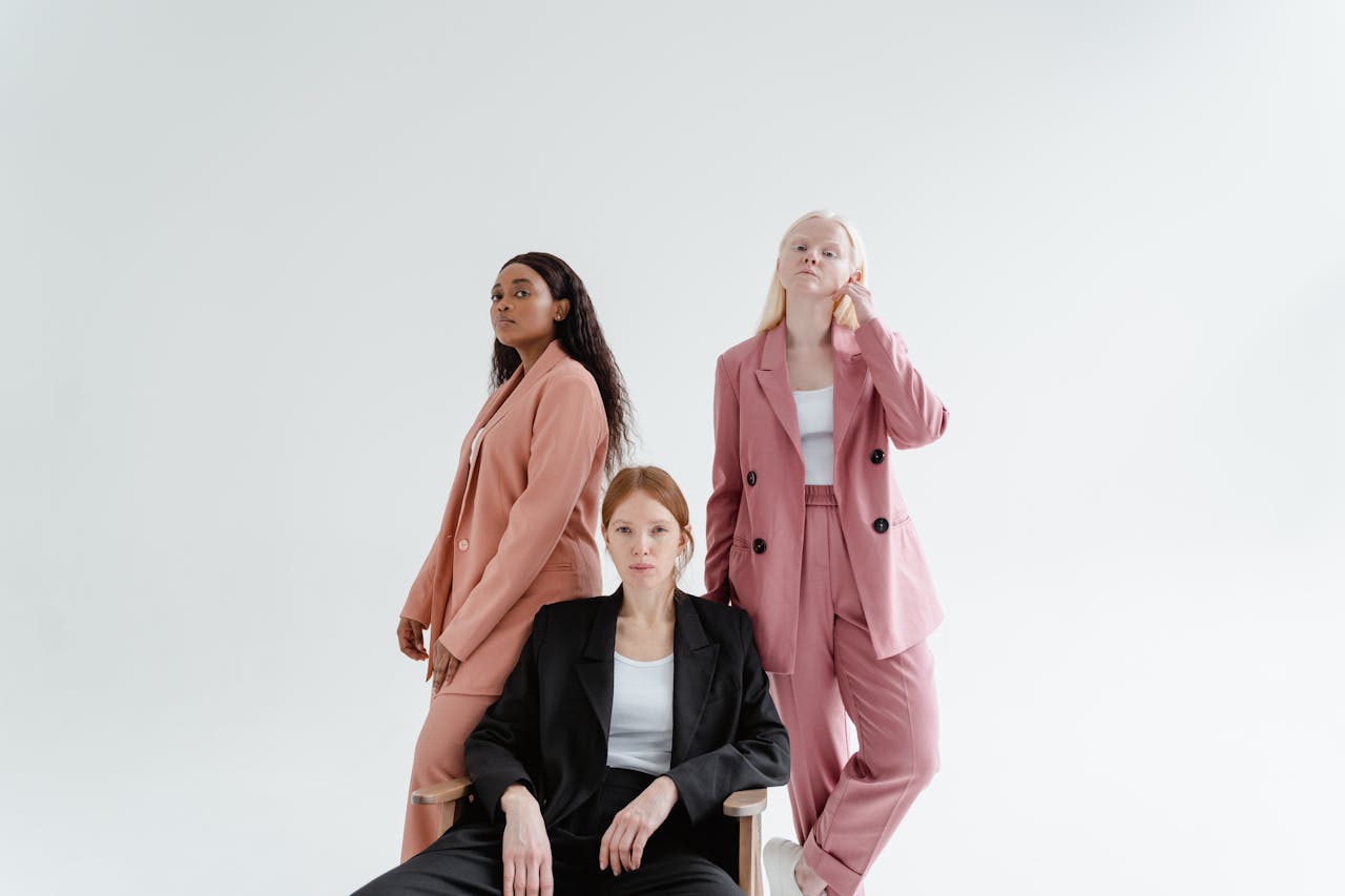 Three diverse businesswomen in stylish suits on a studio white background, exuding confidence.