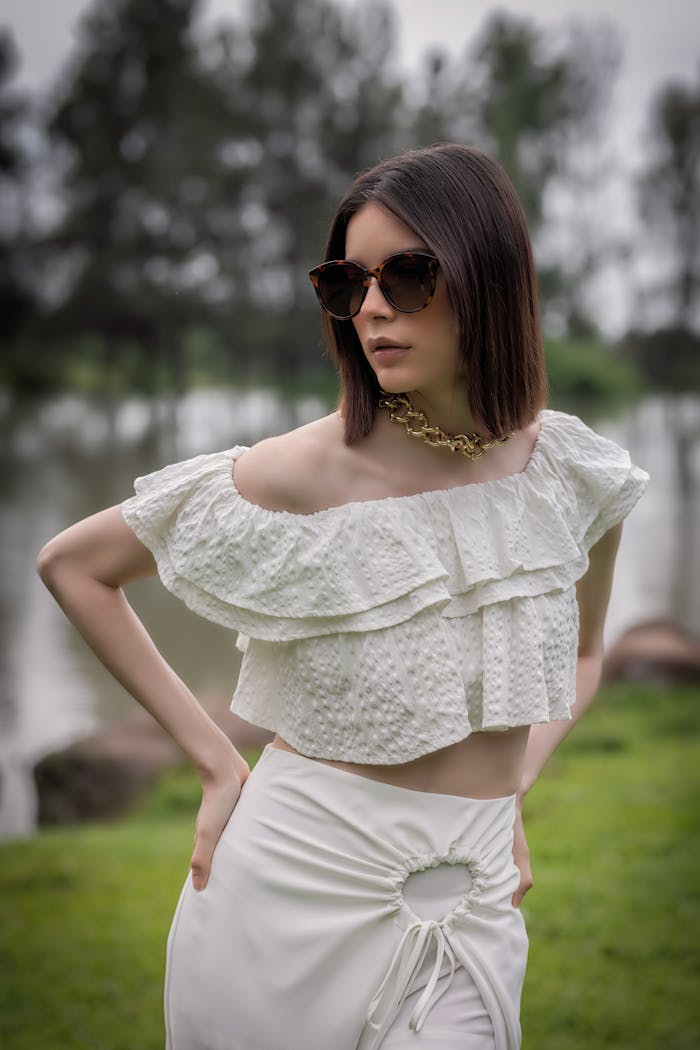 Fashionable woman wearing off-shoulder top and sunglasses outdoors.